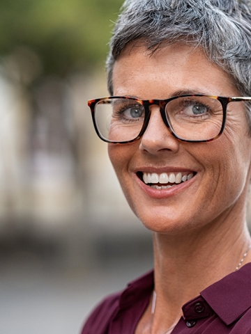Older woman with short hair and glasses smiling