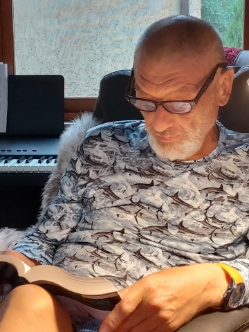 Florin Berca with a book in his lap, reading in his sunroom.