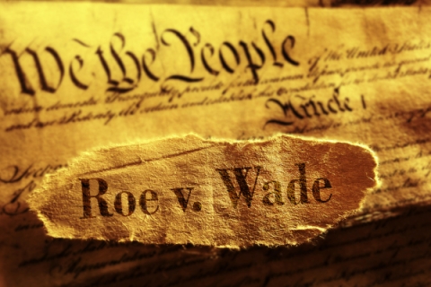 Sepia photograph of torn paper reading "Roe v. Wade" atop the constitution.